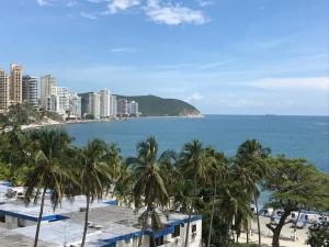 - une vue sur une plage bordée de palmiers et de bâtiments dans l'établissement Apartamento Los Laureles Rodadero, à Santa Marta