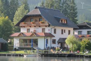 uma grande casa sobre a água com uma doca em Frühstückspension Seerose em Weissensee