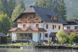 a large house on the water with a dock at Frühstückspension Seerose in Weissensee