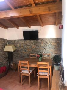 einen Holztisch mit 2 Stühlen und einen TV an einer Steinmauer in der Unterkunft Casa do Tuga in Bragança