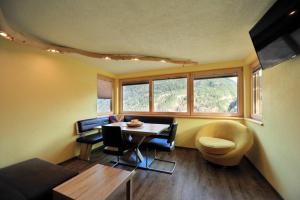 Cette chambre comprend une table, des chaises et des fenêtres. dans l'établissement Appartement Kalkus-Sölden, à Sölden
