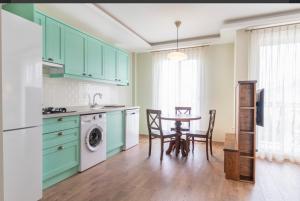 een keuken met groene kasten en een tafel met stoelen bij Defne Residence Selimiye in Marmaris