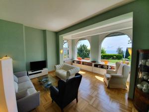 a living room with green walls and white furniture at Villa Serendipità in Gardone Riviera