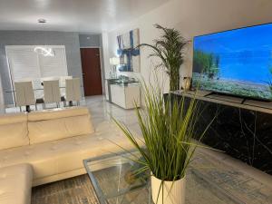 a living room with a white couch and a large screen tv at Ocean view Hollywood in Hollywood
