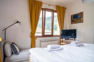 a bedroom with two beds and a tv and a window at Guest House Rossy in Trigrad
