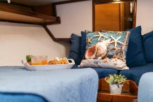 a blue couch with a pillow and a plate of food at Marta Boat B&B in Castelsardo