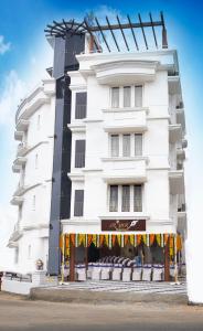 a white building with awning in front of it at Srivar Hotels in Guruvāyūr