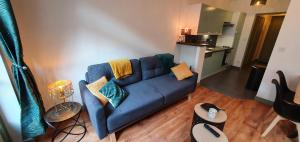 uma sala de estar com um sofá azul e uma cozinha em Les balcons de Dieppe - appartement 1ER étage - certifié 3 étoiles au cœur de la rue piétonne em Dieppe