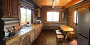 a kitchen in a log cabin with a sink and a table at Cottage Radomyshl' in Radomyshlʼ