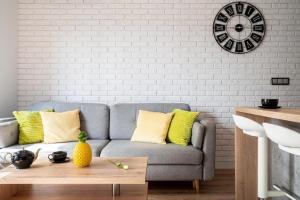 a living room with a couch and a clock on the wall at Art Apart River View Wrocław in Wrocław