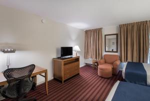 a hotel room with a bed, chair, desk and television at Americas Best Value Inn-Painted Post in Painted Post