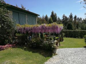 una corona de flores púrpuras colgando sobre un banco en un jardín en Casas da Tapada Briteiros Casa Do Espigueiro, en Guimarães