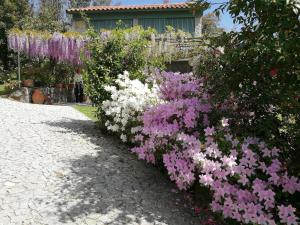 ein Garten mit rosa und weißen Blumen vor einem Haus in der Unterkunft Casas da Tapada Briteiros Casa Do Espigueiro in Guimarães + 9 Fotos