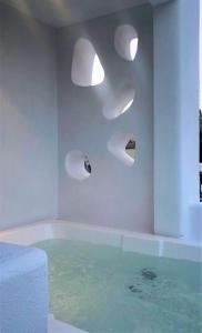 a bathroom with a tub with lights on the wall at Candele Suites in Fira