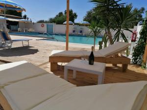 a pool with two beds and a table with a bottle of wine at Le Palme Holidays in Palmadula