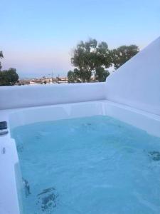 a bath tub filled with blue water next to a wall at Candele Suites in Fira
