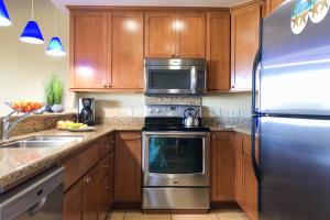 a kitchen with wooden cabinets and a stainless steel refrigerator at Poipu Sands 214 in Kipu