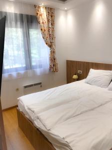 een groot wit bed in een slaapkamer met een raam bij s23 green in Zlatibor