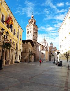 a person walking down a street with a tall tower at Disfruta Teruel in Teruel