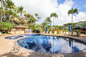 uma piscina num resort com cadeiras e palmeiras em Waikomo Streams 202 em Kipu