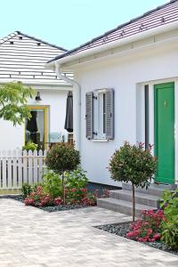 una casa blanca con una puerta verde y flores en The Doors Boutique Apartments en Mosonmagyaróvár