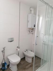 uma casa de banho branca com um WC e um chuveiro em Malvarrosa apartamentos em Valência