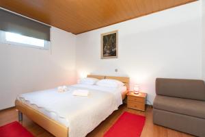 sypialnia z białym łóżkiem i krzesłem w obiekcie Apartman Dobrila w Crikvenicy