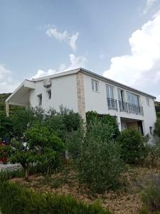 una casa blanca con arbustos delante en tomislav, en Trogir