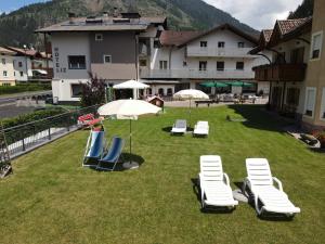 a group of lounge chairs and umbrellas on a lawn at Liz Hotel & Apartments in Predazzo
