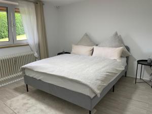 Una cama con sábanas blancas y almohadas en un dormitorio en Ferienwohnung Katzenberg, en Bad Soden-Salmunster
