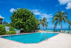 a swimming pool with palm trees and the ocean at Beach Living at Plantation Village BLGS in George Town