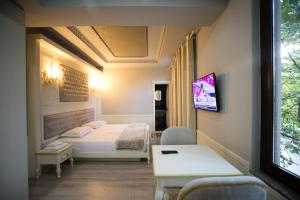 Habitación con cama y TV en la pared. en Hotel Lotus en Tirana