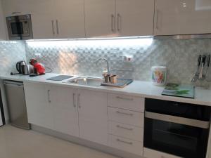 a kitchen with white cabinets and a sink at M&M BLUE LUXURY in Paralia Katerinis