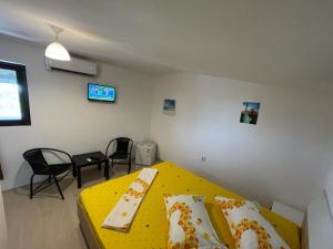 a small room with a yellow bed and chairs at Estelle in Costinesti
