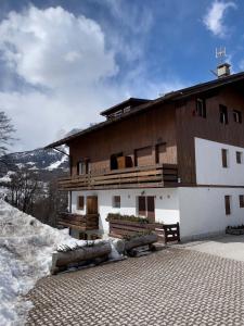 um grande edifício de madeira com neve em frente em Casa Pecol em Cortina dʼAmpezzo