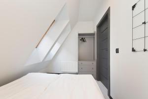 a bedroom with a white bed and a white wall at Apartamenty Zacisze in Gdańsk