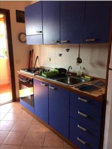 una cucina blu con lavandino e piano cottura di Airport at 25 min by walk - 5 min by walk to commercial center 2 min by walk to touristic port for trip to islands 5 min by walk to bus for city and beaches -Balcony sunset and Sea view-wi fi-air cond-5 persons-pool from 15 june to 15 september PISCINA a Olbia