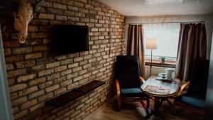 a room with a brick wall with a table and a tv at Browar Osjann - pokoje gościnne in Biała Podlaska