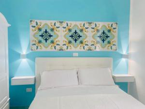 1 dormitorio con cama blanca y pared azul en Cilento Experience rooms, en Marina di Camerota