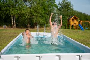 two children playing in a pool with water at Siedlisko Rusko in Darłowo