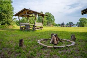 a park with a bench in the grass with a tree stump at Siedlisko Rusko in Darłowo