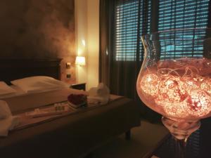 a wine glass sitting on a table next to a bed at Hotel Fidenza in Fidenza