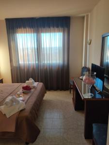 Hotel Fidenza في فيدينسا: غرفة فندقية بسرير وطاولة ونافذة