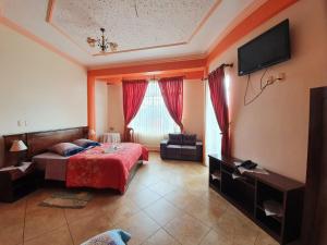 a bedroom with a bed and a television and a couch at Hotel El Cristo in Cobija