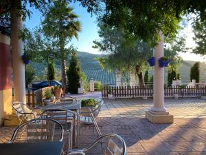 a patio with tables and chairs and a view of the water at Complejo turístico y alojamientos Fuente de la Salud in Baena