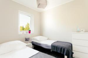 Dos camas en una habitación blanca con ventana. en Brzozowy Zakątek, en Dąbki 55 fotos más