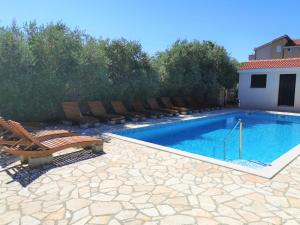 a swimming pool with chairs next to a house at Lenka Apartments II in Novalja