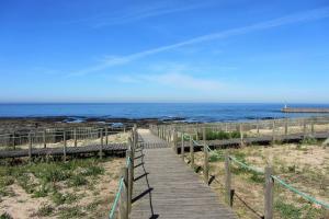 a wooden path to the beach with the ocean in the background at Casa do Remo Praia da Aguda in Arcozelo