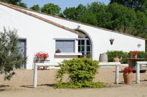 une maison blanche avec une fenêtre et des plantes devant elle dans l'établissement Mas du Menage en Camargue Manade Clauzel, à Saintes-Maries-de-la-Mer