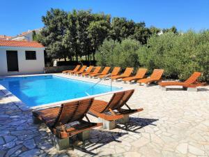 a swimming pool with lounge chairs and a swimming pool at Lenka Apartments I in Novalja